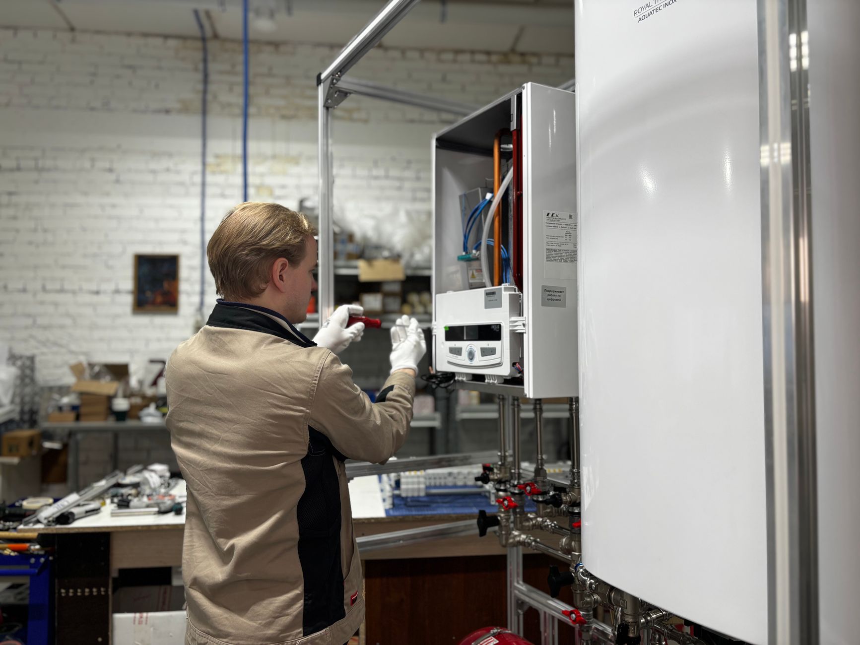 Technician adjusting controls on a wall-mounted heating unit in a workshop